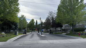 View of asphalt street with a gate, street lighting, curbs, and a gated entry
