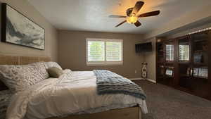 Bedroom featuring carpet flooring, a ceiling fan, and a textured ceiling