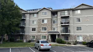 View of apartment building / complex featuring uncovered parking