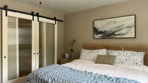 Bedroom with a barn door and a textured ceiling