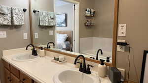 Ensuite bathroom featuring double vanity and a tub