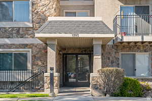Property entrance featuring stone siding, french doors, and stucco siding