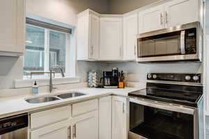 Kitchen featuring stainless steel appliances, white cabinets, and light countertops