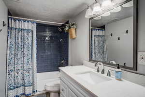 Bathroom with a textured ceiling, vanity, and shower / bath combo