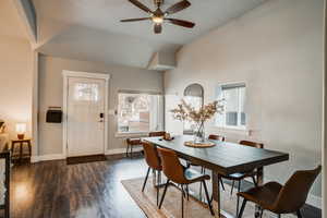 Dining area featuring a ceiling fan, dark wood-style flooring, and lofted ceiling