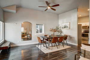 Dining room featuring ceiling fan, dark wood-style floors, vaulted ceiling, recessed lighting, and arched walkways