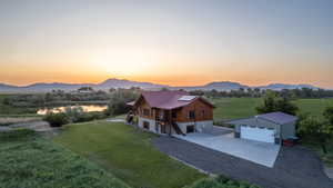 View of front of house with driveway, a front lawn, a detached garage, and solar panels