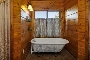 Full bath featuring wooden walls, a soaking tub, and tile patterned flooring