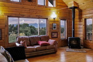 Living area with a wood stove, wood walls, plenty of natural light, hardwood floors, and wood ceiling