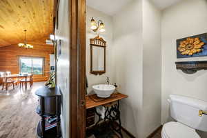 Half bath featuring wood walls, hardwood finished floors