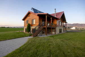Back of house at dusk with a lawn, stairs, a metal roof, and a mountain view