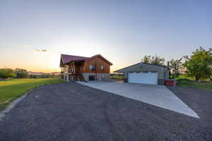 View of front of home featuring an outbuilding, a garage, a lawn, and stairway