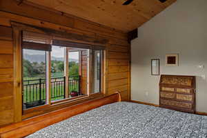 Primary bedroom featuring vaulted ceiling, wooden ceiling, a mountain view, and wood walls