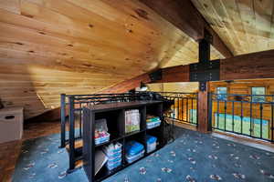 Loft featuring wooden ceiling, vaulted ceiling, and wooden walls