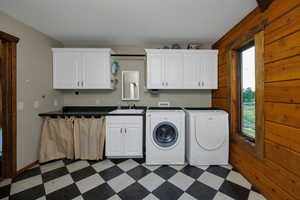 Laundry room featuring dark floors, cabinet space, independent washer and dryer, and wooden walls