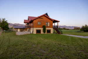 View of front of house with stairs, a lawn, a metal roof, and a deck with mountain view