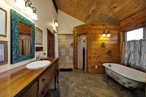 Primary bathroom featuring wood ceiling, vanity, a tile shower, a freestanding bath, and vaulted ceiling