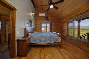 Primary bedroom featuring lofted ceiling, wood ceiling, wooden walls, a mountain view, and hardwood flooring