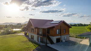 View of home's exterior with solar panels, a yard, a water and mountain view, and a metal roof