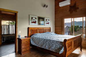 Primary bedroom with an AC wall unit, a mountain view, hardwood finished floors, wood walls, and access to outside