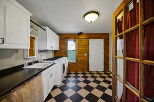Laundry area featuring cabinet space, light floors, washer and clothes dryer and wood walls