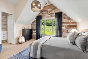 Bedroom with wood walls, wood finished floors, and a walk in closet