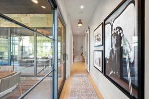Hallway with plenty of natural light, light wood-style flooring, stairway, recessed lighting, and a barn door