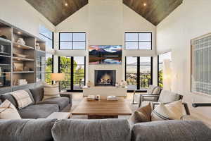 Living area with high vaulted ceiling, wooden ceiling, a large fireplace, and recessed lighting