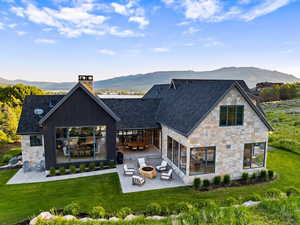 Rear view of house featuring an outdoor fire pit, a patio area, and stone siding
