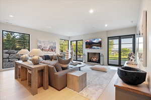 Living room with light wood-style flooring, a large fireplace, and recessed lighting