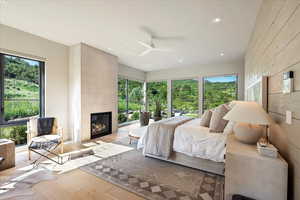 Bedroom with wood finished floors, a tile fireplace, recessed lighting, and ceiling fan