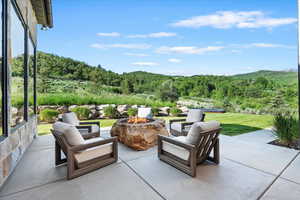 View of patio / terrace featuring an outdoor fire pit, a view of trees, and a mountain view