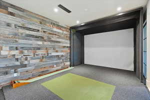 Recreation room with golf simulator, carpet floors, recessed lighting, and wooden walls