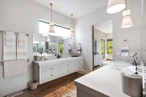 Full bathroom featuring vanity, wood finished floors, and a towering ceiling