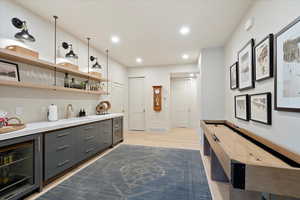 Indoor wet bar with wine cooler, light wood finished floors, and recessed lighting