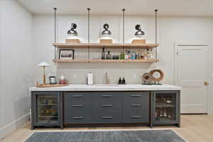 Indoor bar featuring wine cooler and wood finished floors