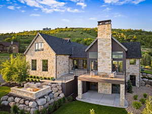 Back of property with stone siding, a chimney, and a patio
