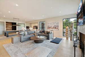 Living area with a large fireplace, light wood-style flooring, and recessed lighting