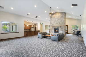 Carpeted living area featuring a fireplace, high vaulted ceiling, and recessed lighting