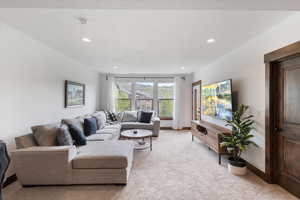 Living area with light carpet and recessed lighting