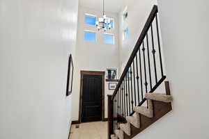 Foyer entrance with a chandelier, stairs, a high ceiling, and light tile patterned floors