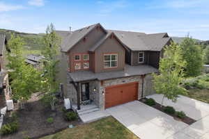 View of front of property featuring stone siding, driveway, and an attached garage