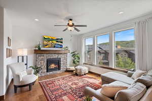 Living room with a ceiling fan, a fireplace, wood finished floors, recessed lighting, and a textured ceiling