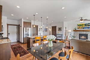 Dining space with a ceiling fan, a fireplace, wood finished floors, and recessed lighting