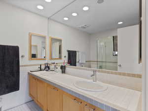 Primary Bathroom featuring double vanity, a shower stall, recessed lighting, tile patterned floors, and a wainscoted wall