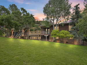Front view of house featuring a lawn, brick siding, and a wooden deck