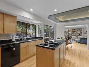 Kitchen with black appliances, light wood-style floors, recessed lighting, light brown cabinetry, and a center island