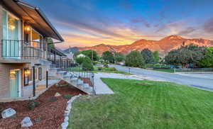 Yard at dusk with stairway, a mountain view, and a yard