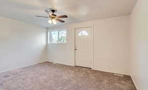Entrance foyer featuring a ceiling fan and carpet