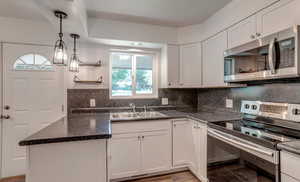 Kitchen with stainless steel appliances, plenty of natural light, open shelves, and white cabinetry